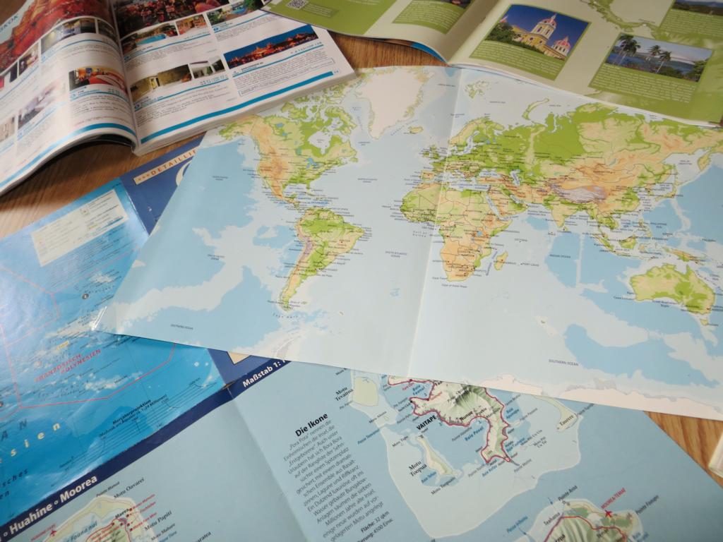 Reiseplanung, mit Landkarte, Magazinen und Reiseführern